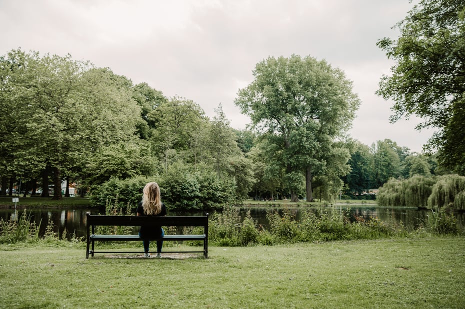 Vrouw zit rustig op een bankje in een park